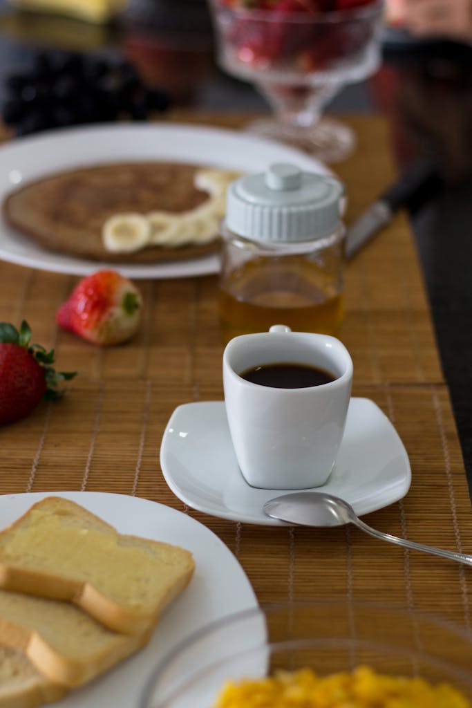 A cozy breakfast setting with coffee, pancakes, toast, and fresh strawberries.