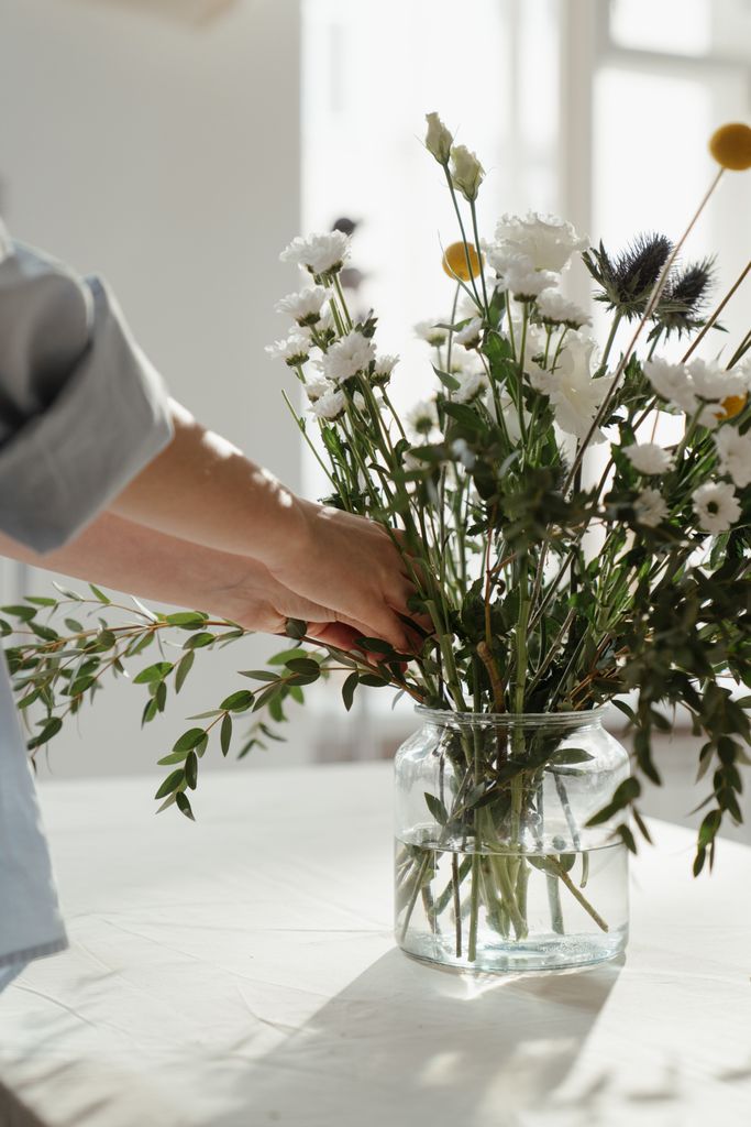 A serene floral bouquet in a glass vase with natural sunlight.